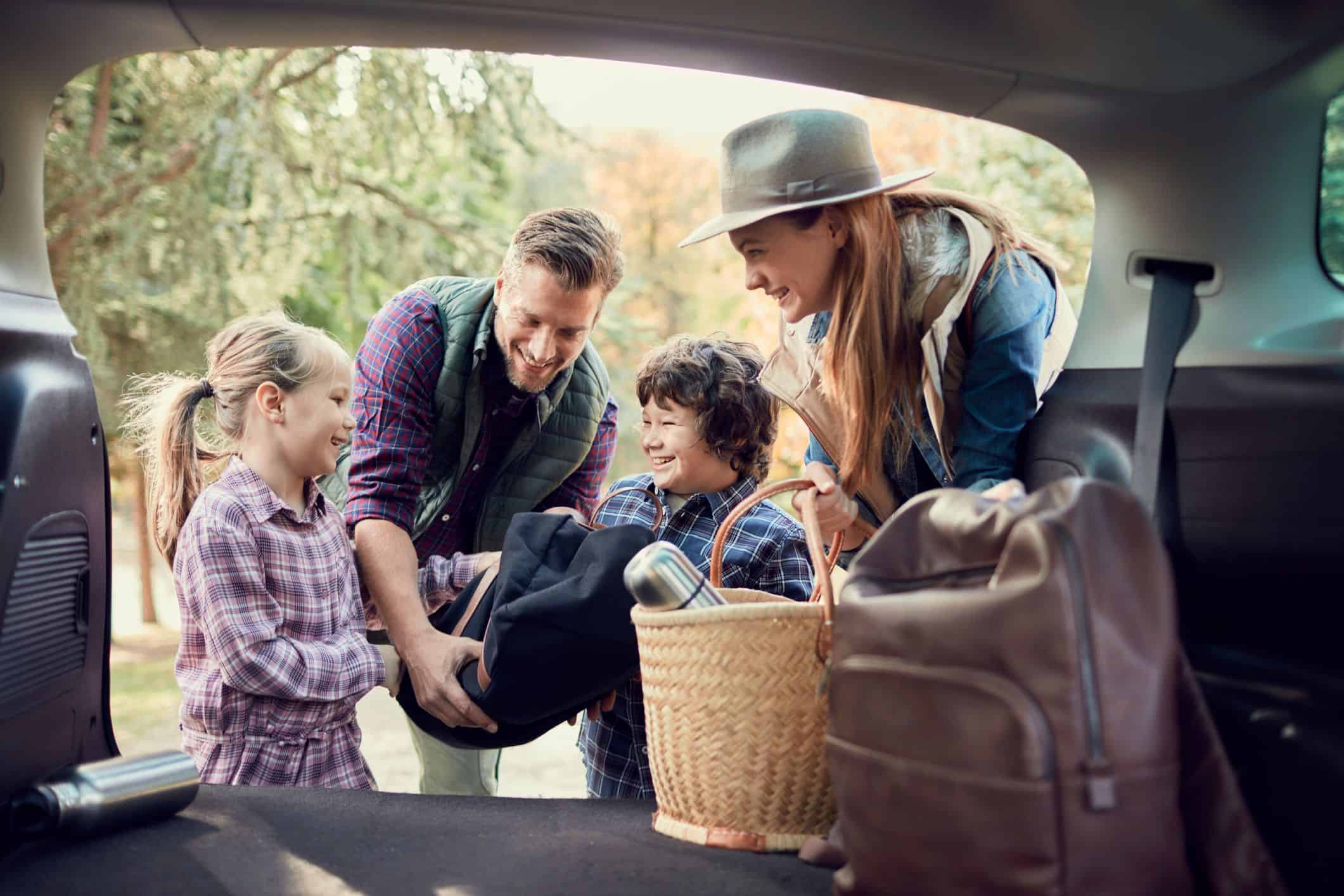 pais com seus filhos colocando malas no carro descubrindo como é viajar com crianças