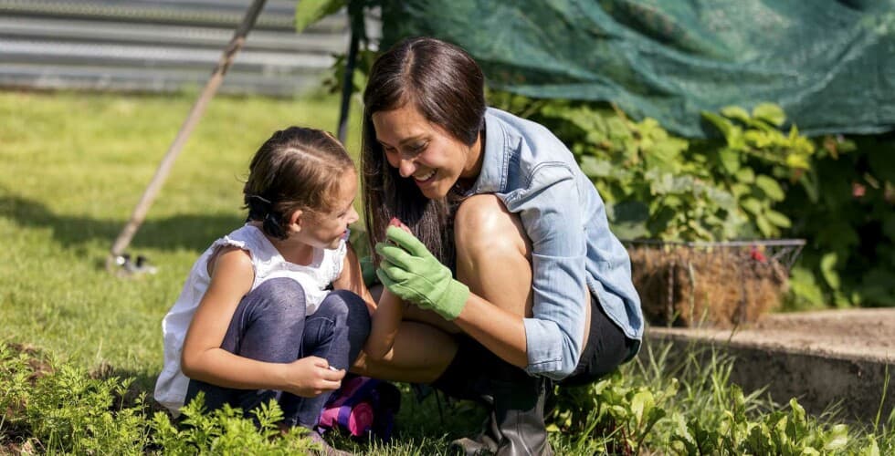 Imagem de uma mulher e uma criança mexendo numa horta