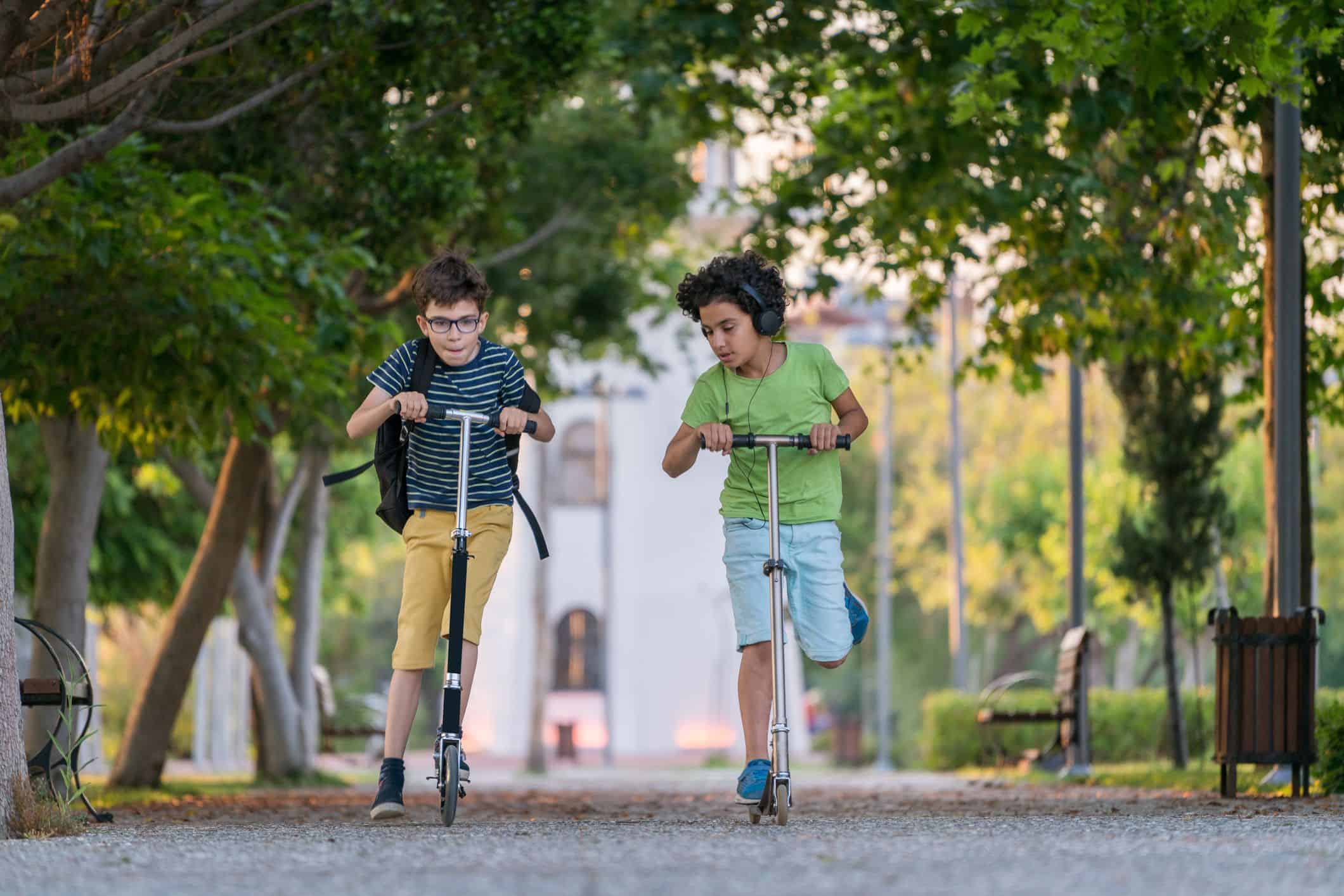 Imagem de dois meninos andando de patinete
