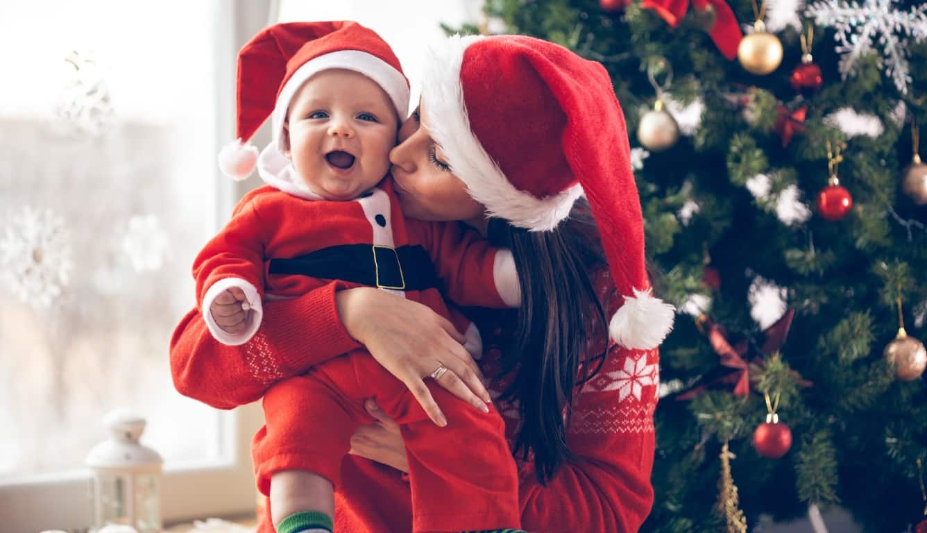 Imagem de uma mãe e um bebê vestidos para o Natal