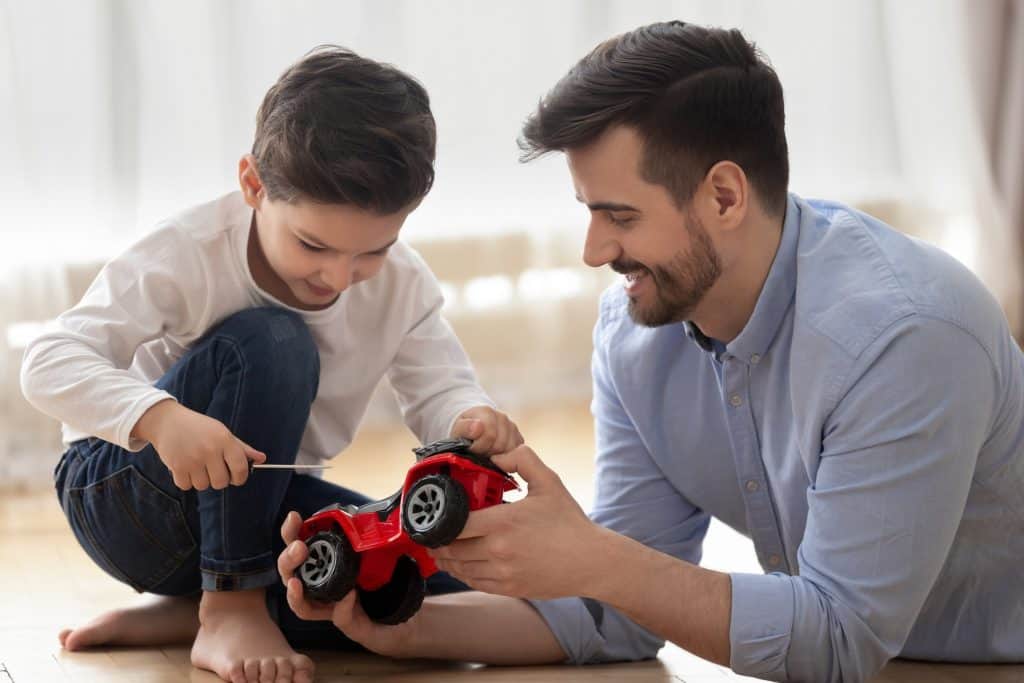 o que é hot wheels: adulto e criança brincando com carrinho vermelho de brinquedo|