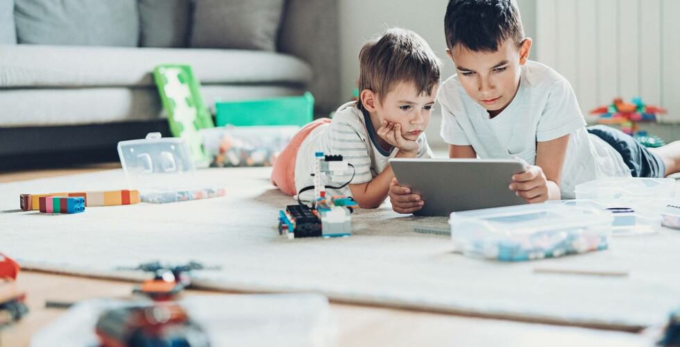 Imagem de duas crianças observando a tela de um tablet