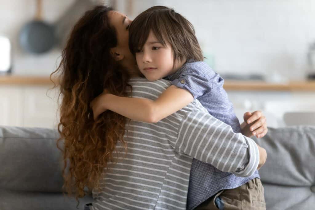 criança abraçando a mãe na sala de casa com medo expressando a ansiedade de separação