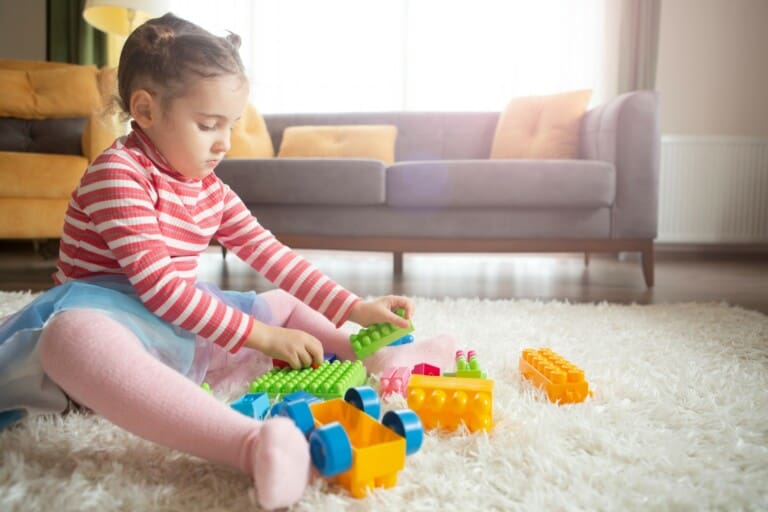 menina sentada na sala brincando com alguns dos brinquedos mais vendidos do mercado