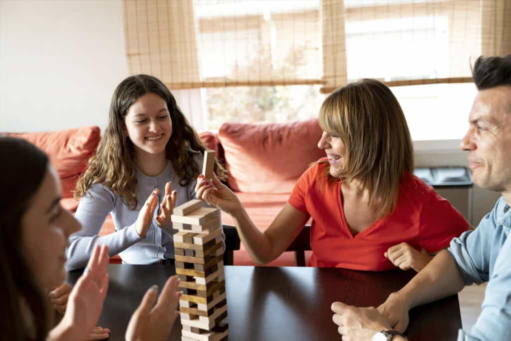 grupo de amigos jogando jenga na sala para representar jogos para adultos