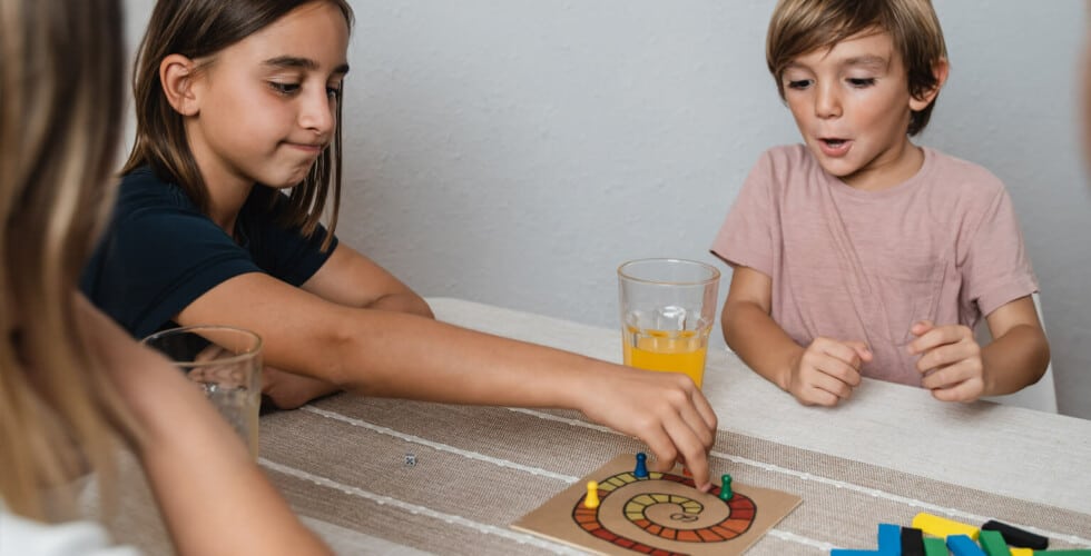 Imagem de duas crianças brincando com os melhores jogos de tabuleiro.