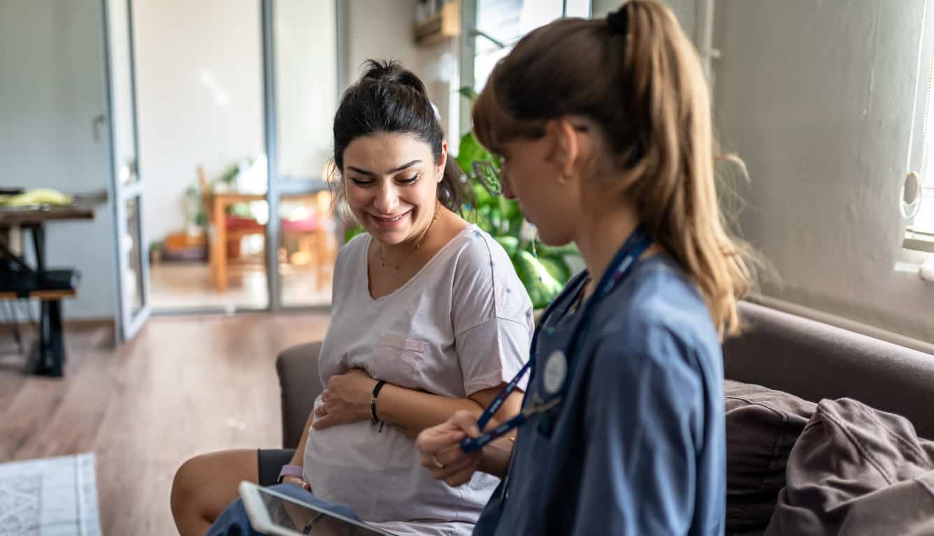 Imagem de duas mulheres conversando. Uma delas está grávida.