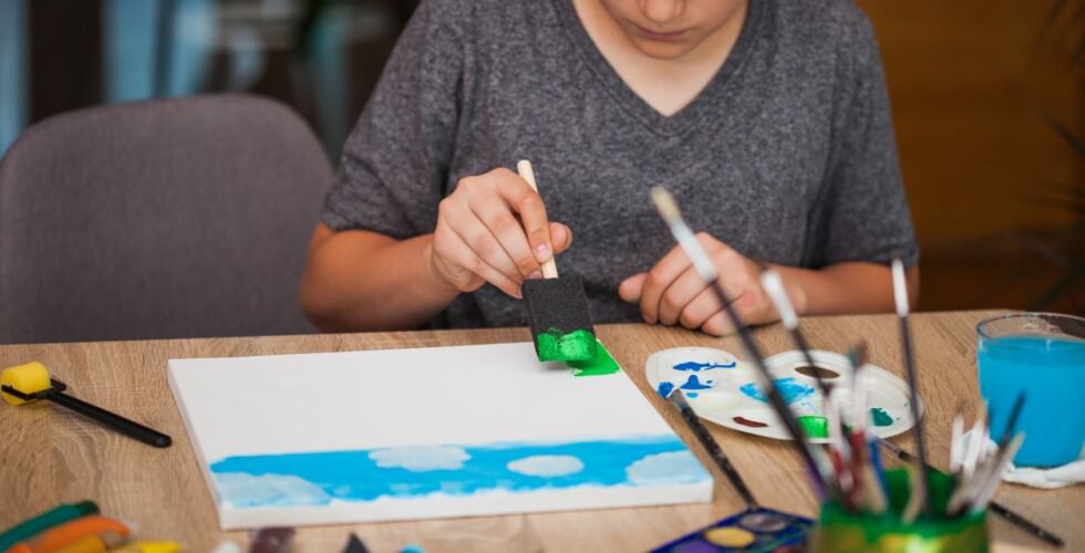 Imagem de uma criança fazendo uma pintura com esponja.