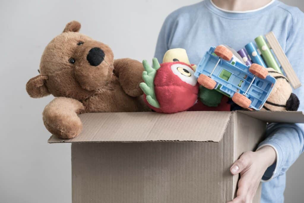 Imagem de uma criança carregando uma caixa com brinquedos para doação.