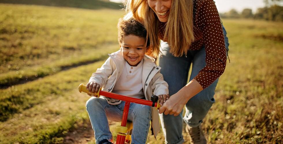 Imagem de um adulto ensinando uma criança a andar de bicicleta.