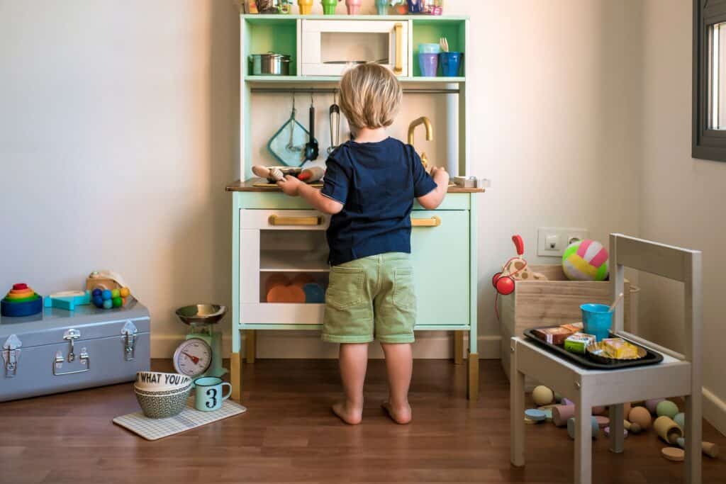 Imagem de uma criança brincando em uma cozinha de brinquedo.
