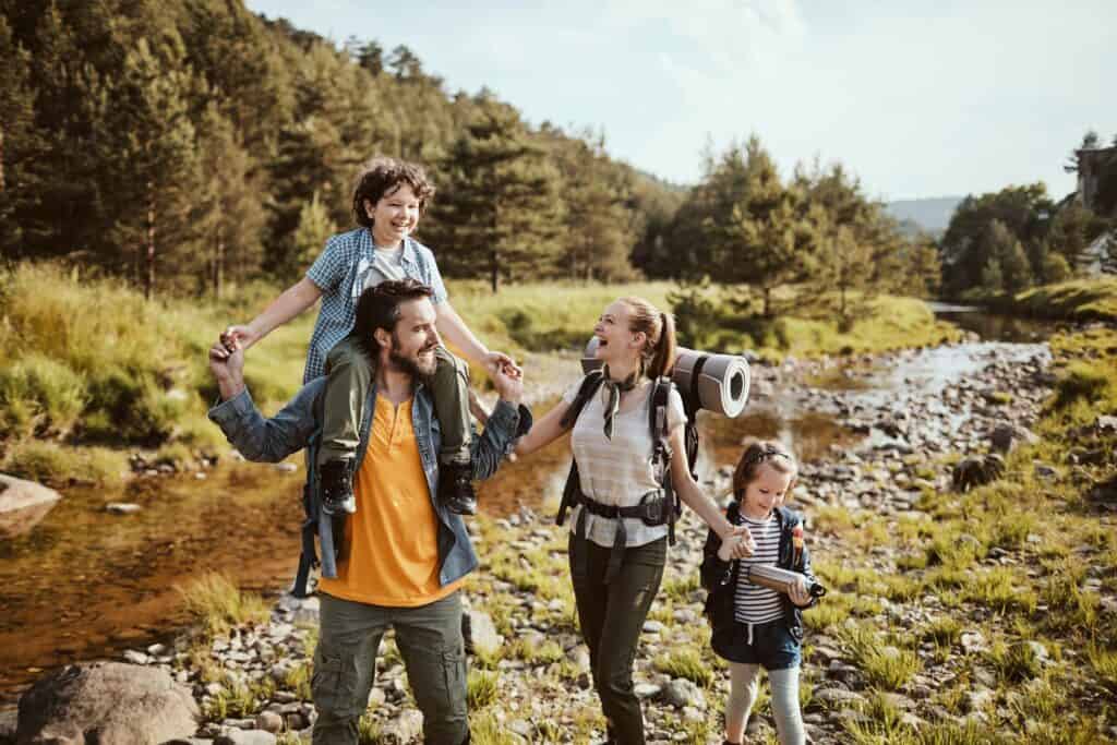 pais com seus filhos em ambiente montanhoso com mochilas de acampamento descubrindo como é viajar com crianças