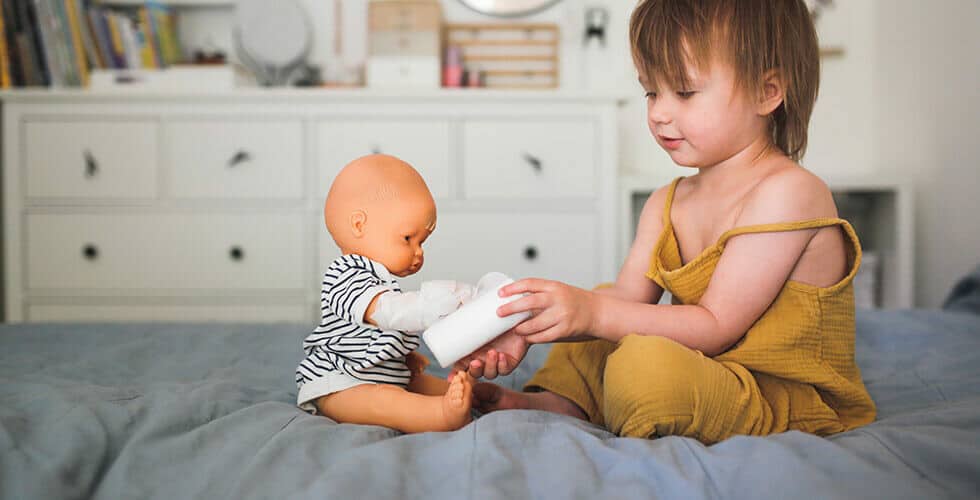 Imagem de uma criança brincando com uma boneca
