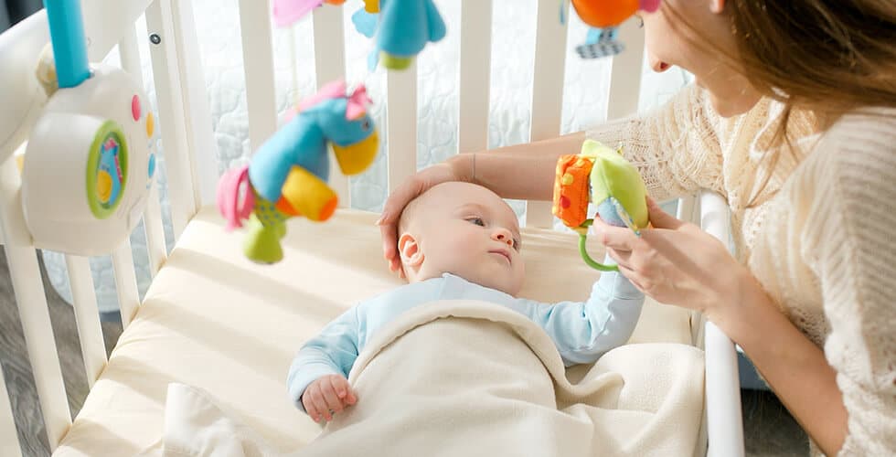 mãe brincando com bebê com mobiles no berço, um brinquedo para recém-nascido
