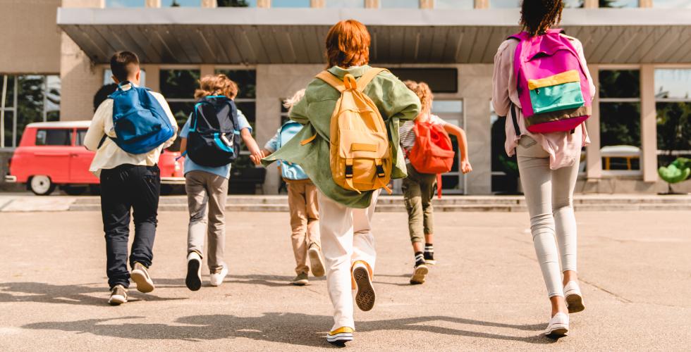crianças correndo em porta da escola com mochila