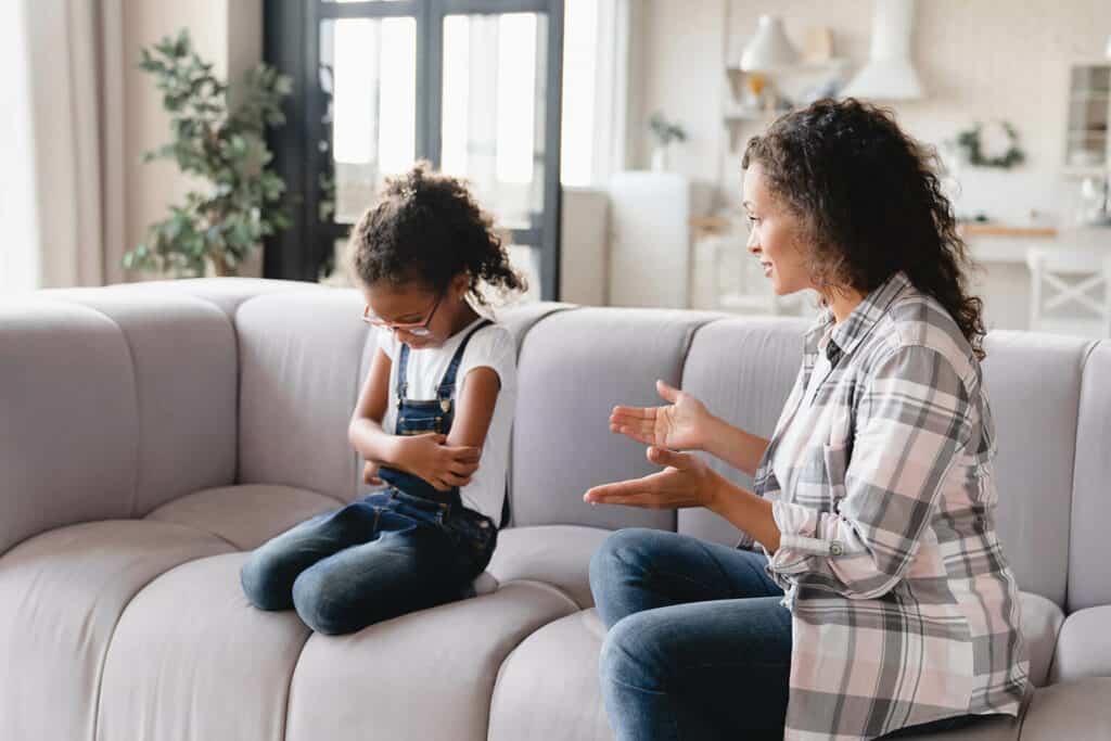 mãe conversando com filha sentada no sofá sobre consumo infantil