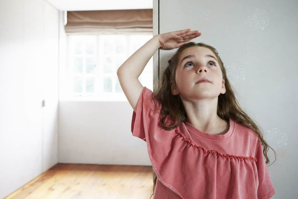 menina na pre-adolescência medindo seu tamanho na parede de casa