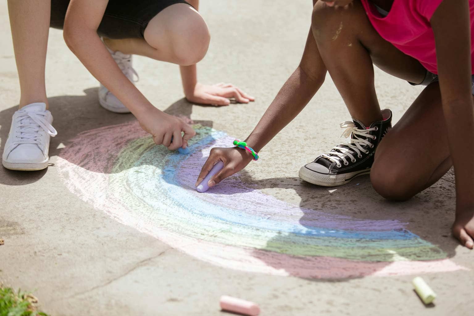 crianças desenhando um arco-iris na rua representando amizade infantil