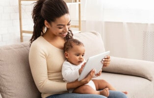 Imagem de uma mulher com um bebê no colo assistindo desenho em tablet