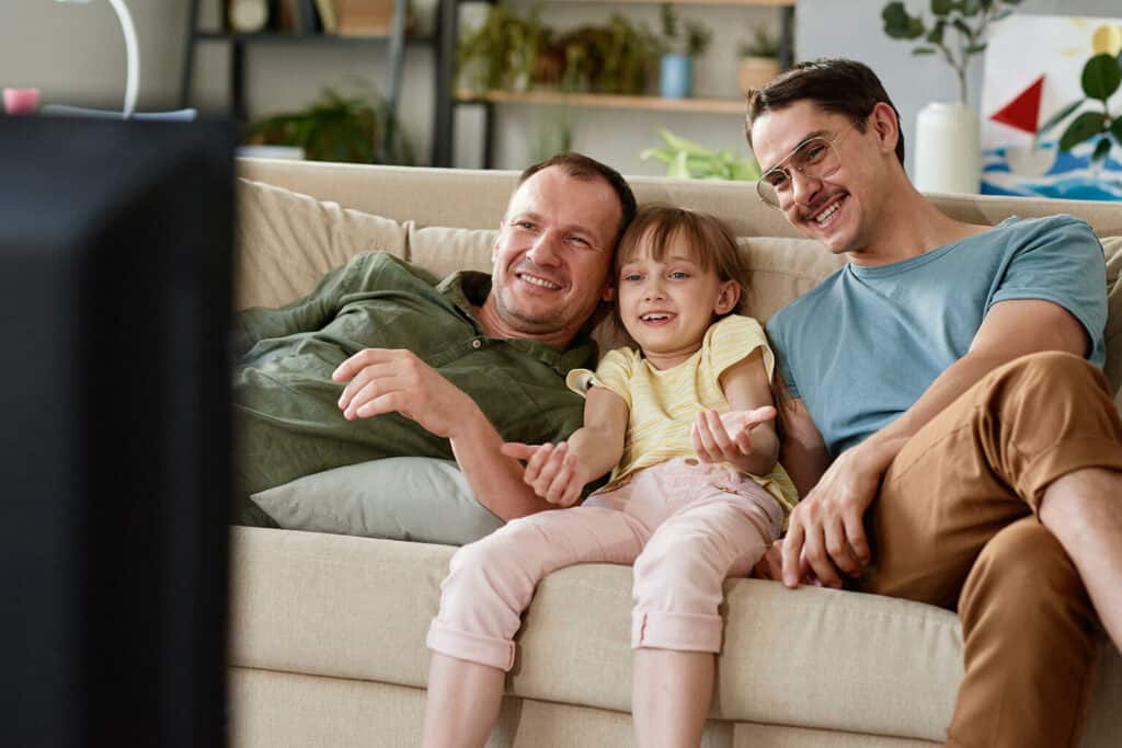 pais e filha sentados no sofá assistindo filme durante as comemorações do dia dos pais