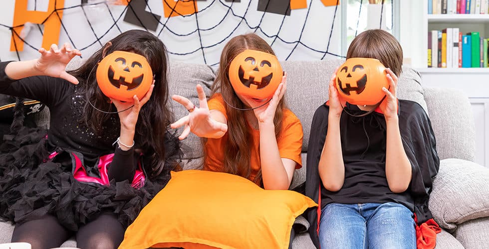 crianças com fantasia de halloween sentados no sofá