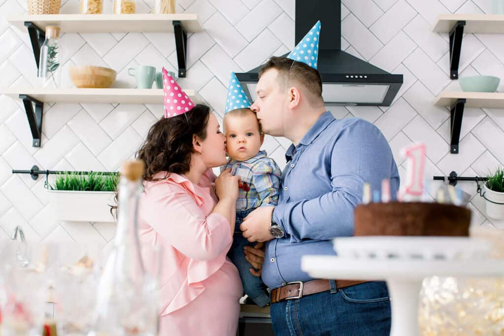 mãe e pai beijando bebê no rosto durante a comemoração dasua festa de 1 ano