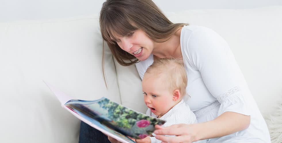 mãe incentivando leitura para bebês lendo livro com seu filho no colo