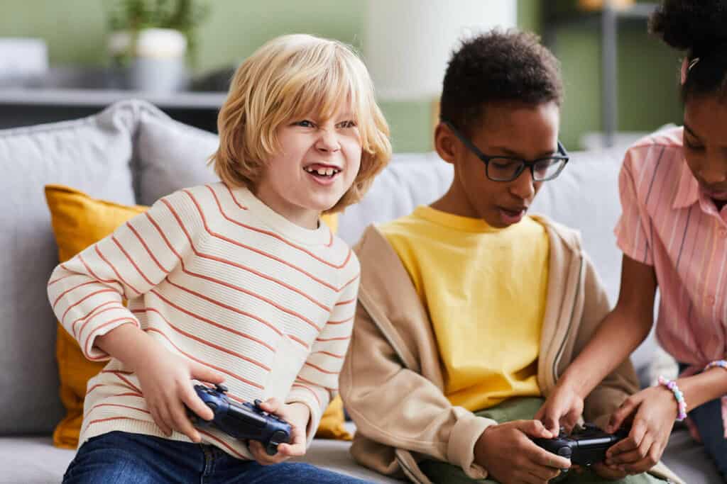 dois meninos e uma menina sentados no sofá aprendendo a jogar os melhores jogos do xbox one