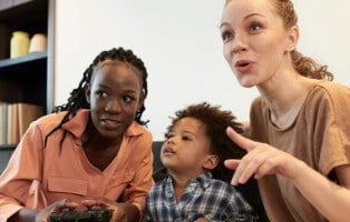 Imagem de duas mulheres e uma criança jogando videogames