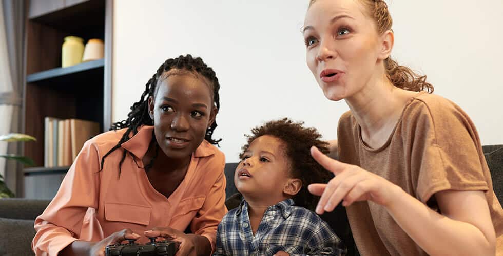 Imagem de duas mulheres e uma criança jogando videogames