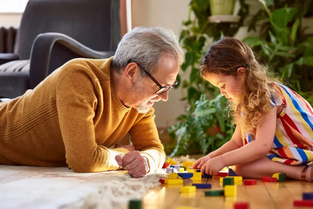 Imagem de um avô e uma neta brincando com blocos de montar
