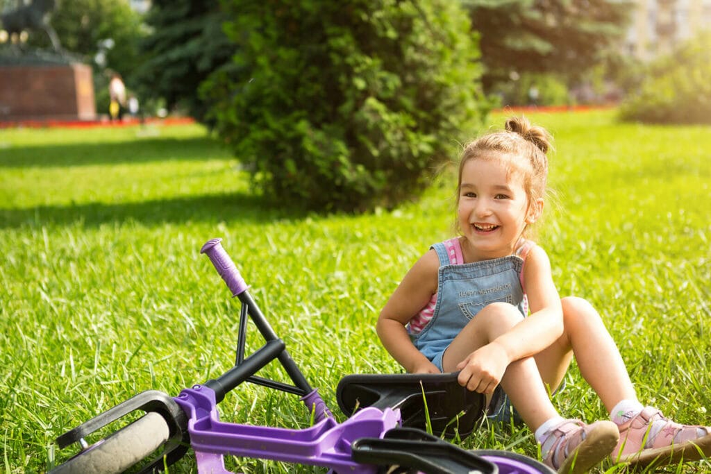 Imagem de uma menina sentada ao lado de uma bicicleta