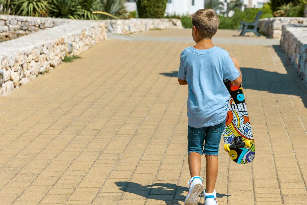 menino segurando skate andando em parque represetando como aprender a andar de skate