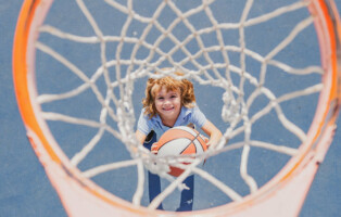 criança descobrindo como jogar basquete enquanto arremesa bola na cesta