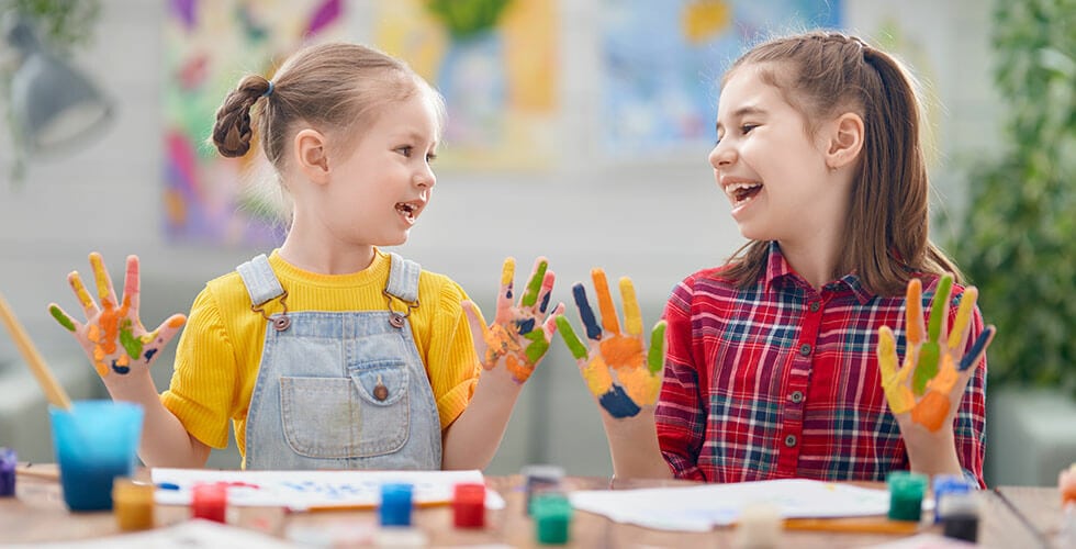Imagem de duas crianças se divertindo com materiais de pintura