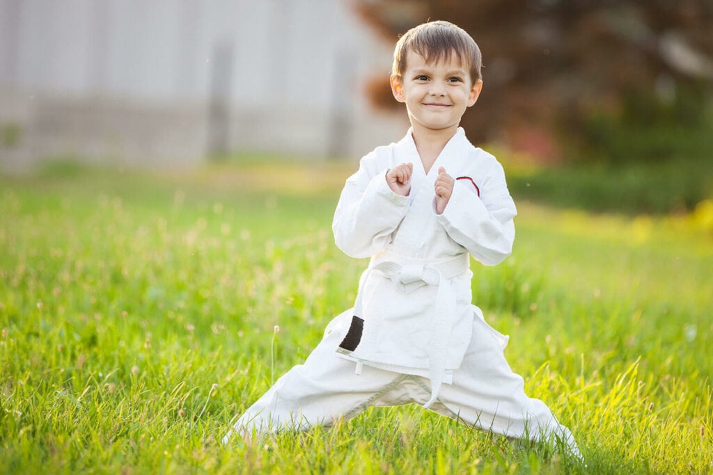 Imagem de um menino vestido com roupas para praticar jiu-jitsu infantil