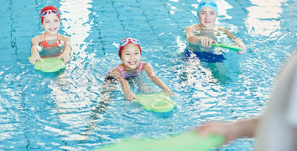 Imagem de um grupo de crianças aprendendo numa aula de natação infantil