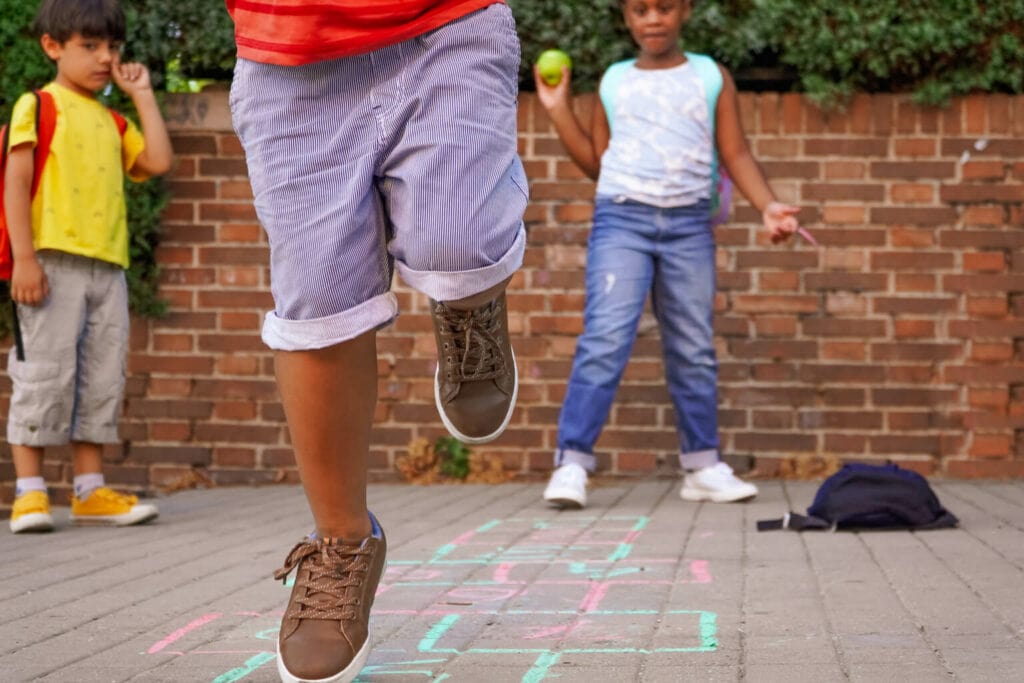 crianças se divertindo jogando amarelinha uma das brincadeiras de rua mais populares