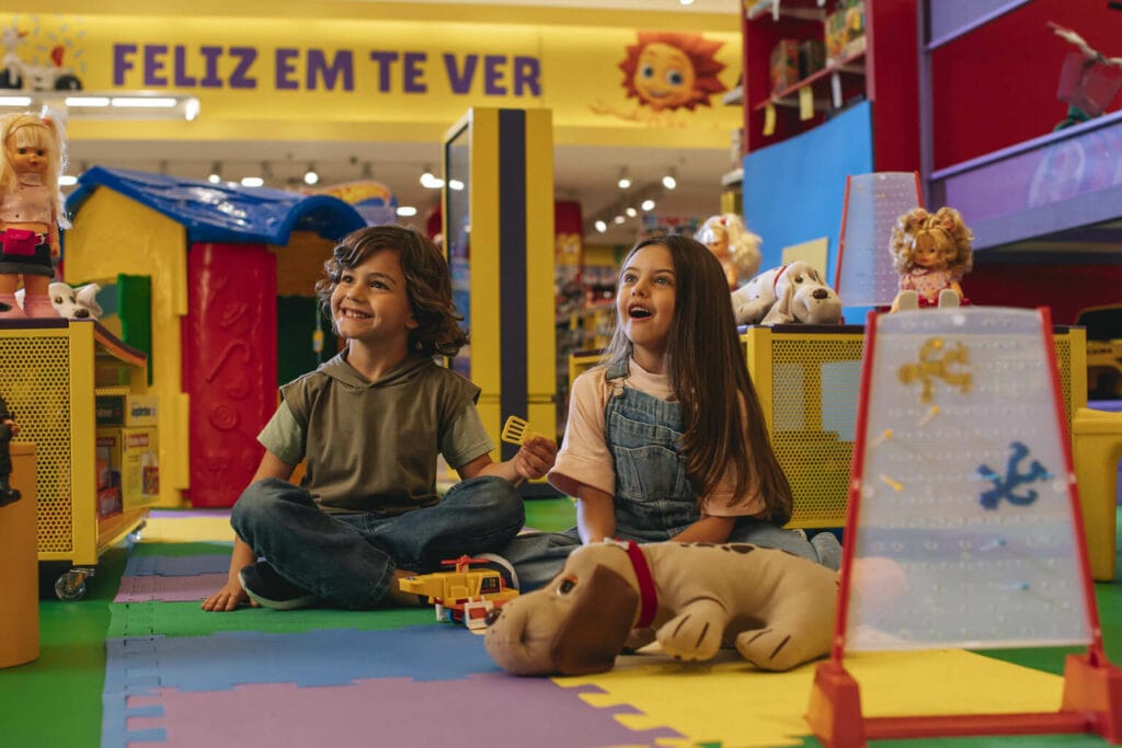 Imagem de duas crianças sentadas se divertindo com brinquedos antigos da Estrela
