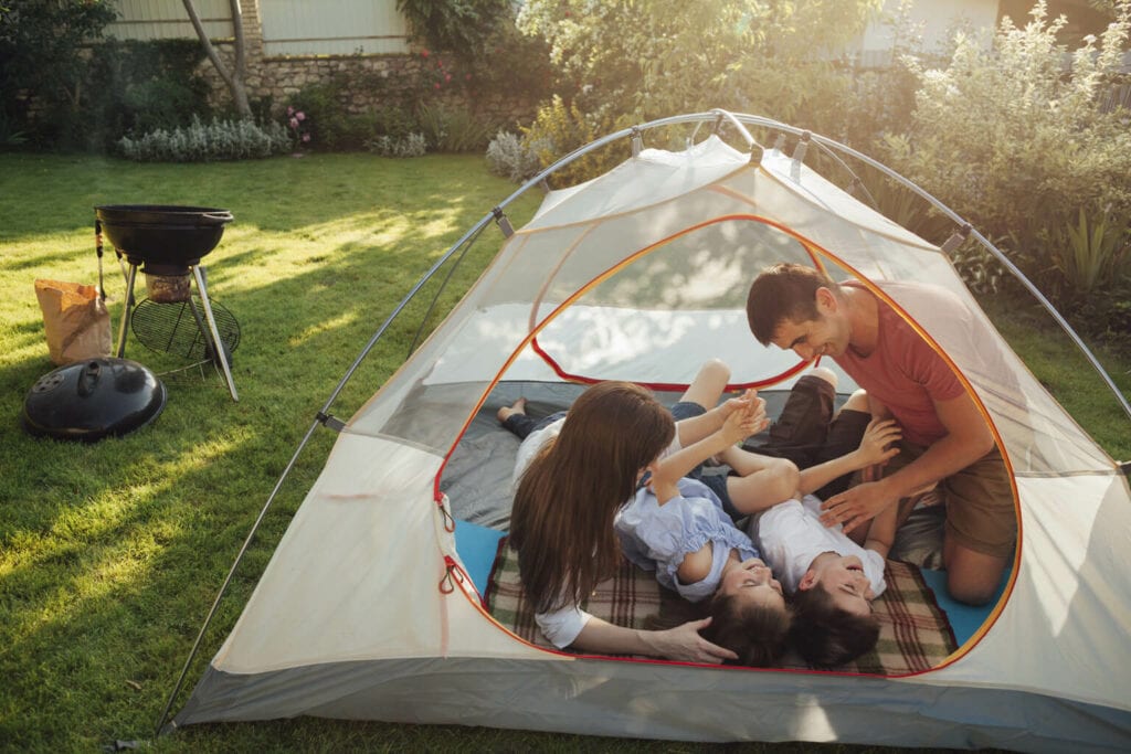 família brincando de acampamento no quintal durante as férias de verão