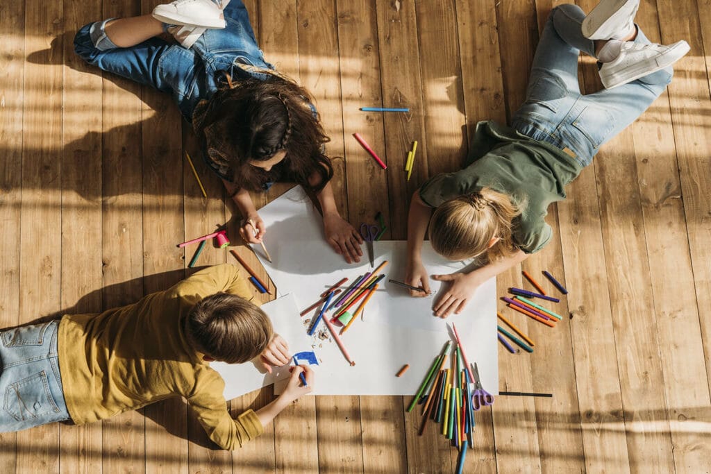 Imagem de três crianças colorindo um desenho