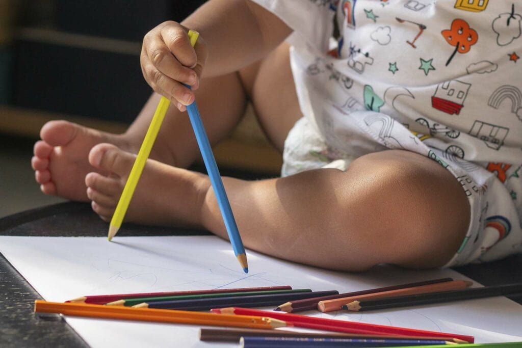 criança brincando com lápis enquanto se diverte com os desenhos para colorir de harry potter