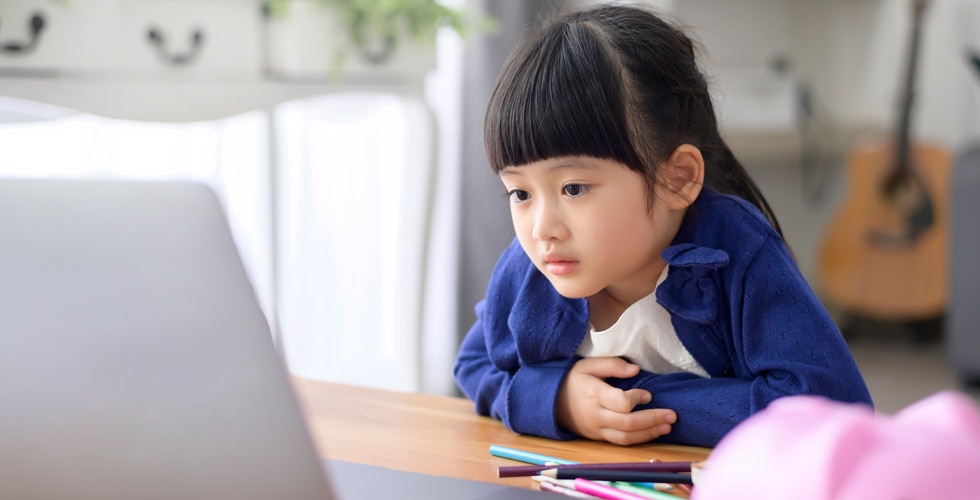 menina asiática olhando para tela de notebook representando crianças na internet