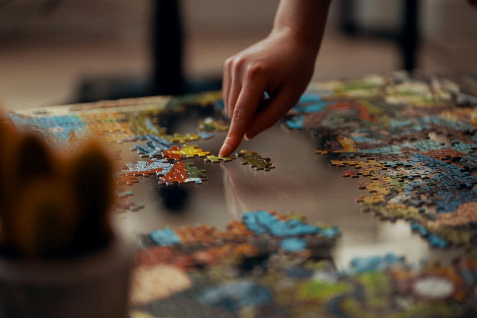 pessoa mexendo peça sob a mesa representando qual é o maior quebra-cabeças do mundo