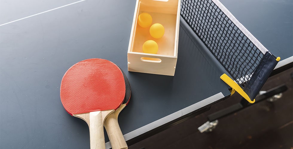 raqueta e bolinhas em cima da mesa representando as regras do tênis de mesa