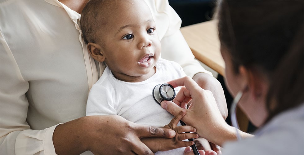 médica com estetóscopio em frente a criança representando a saúde do bebê