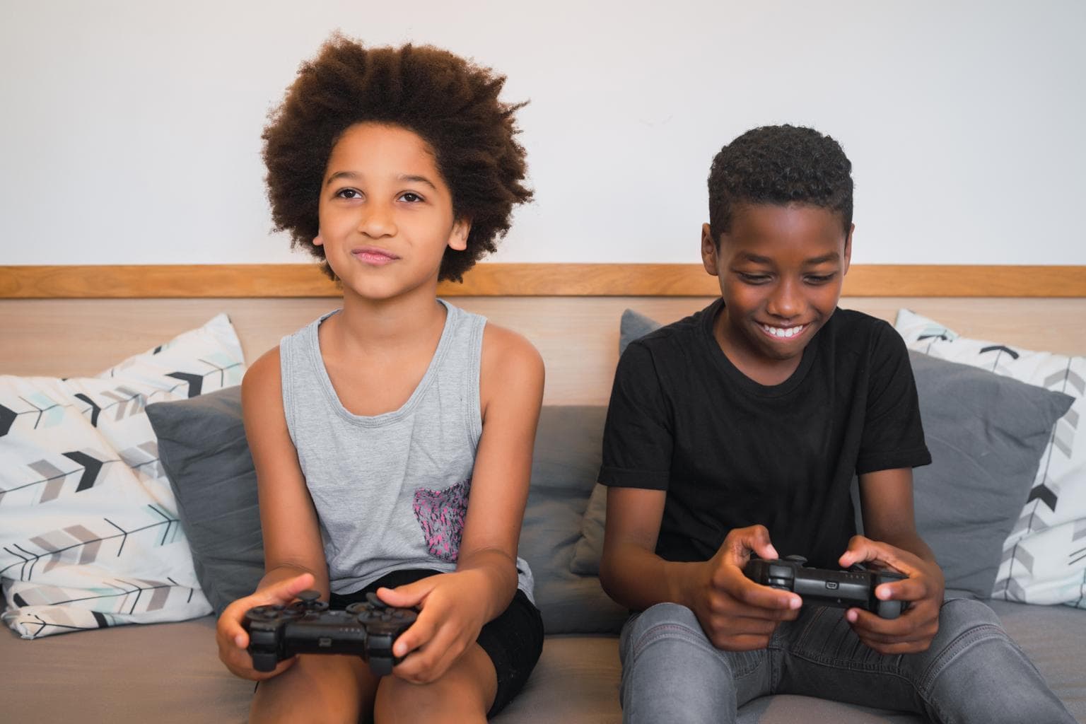 dois meninos sentados no sofá segurando controle de vídeogame representando os melhores jogos para ps4