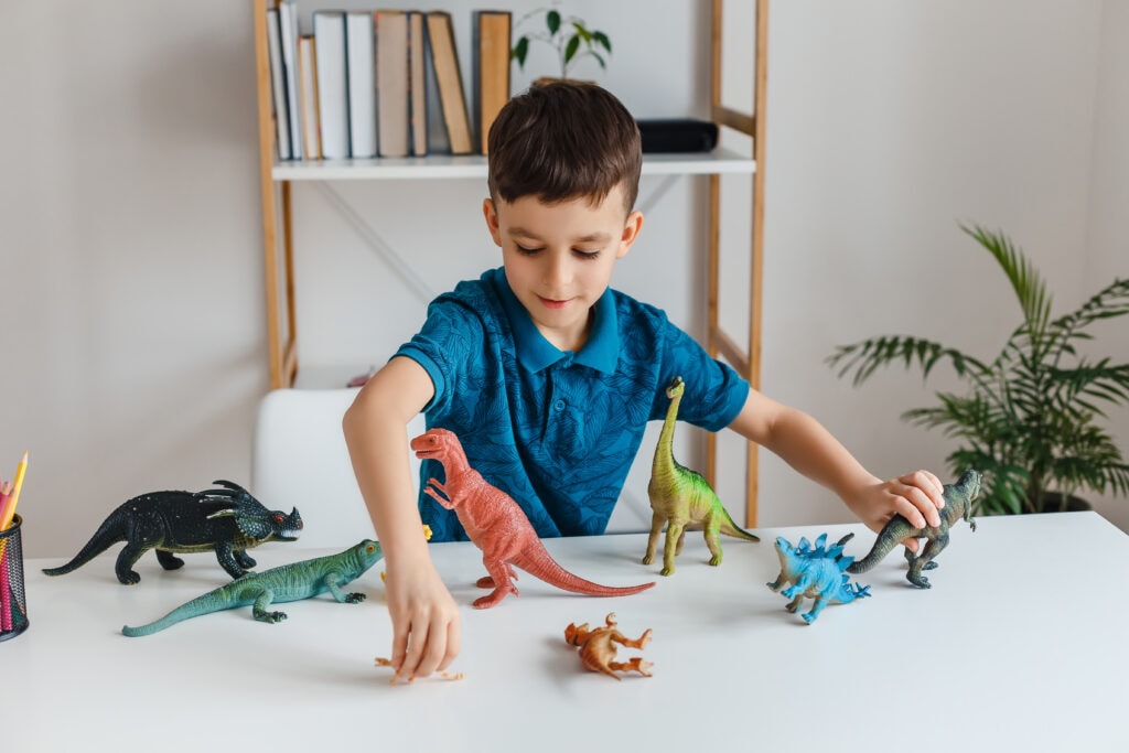 criança brincando com bonecos representando brincadeira de dinossauro