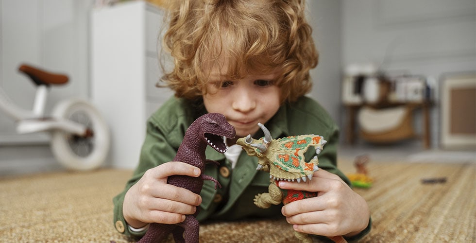 criança se divertindo com bonecos durante brincadeira de dinossauro
