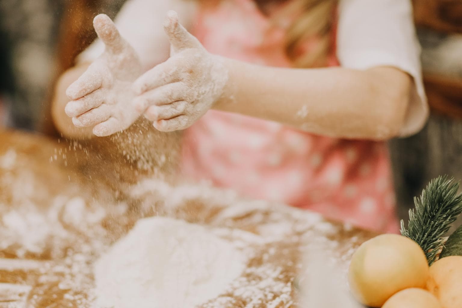mão de criança com farinha e mesa com massa representando brincar de cozinhar